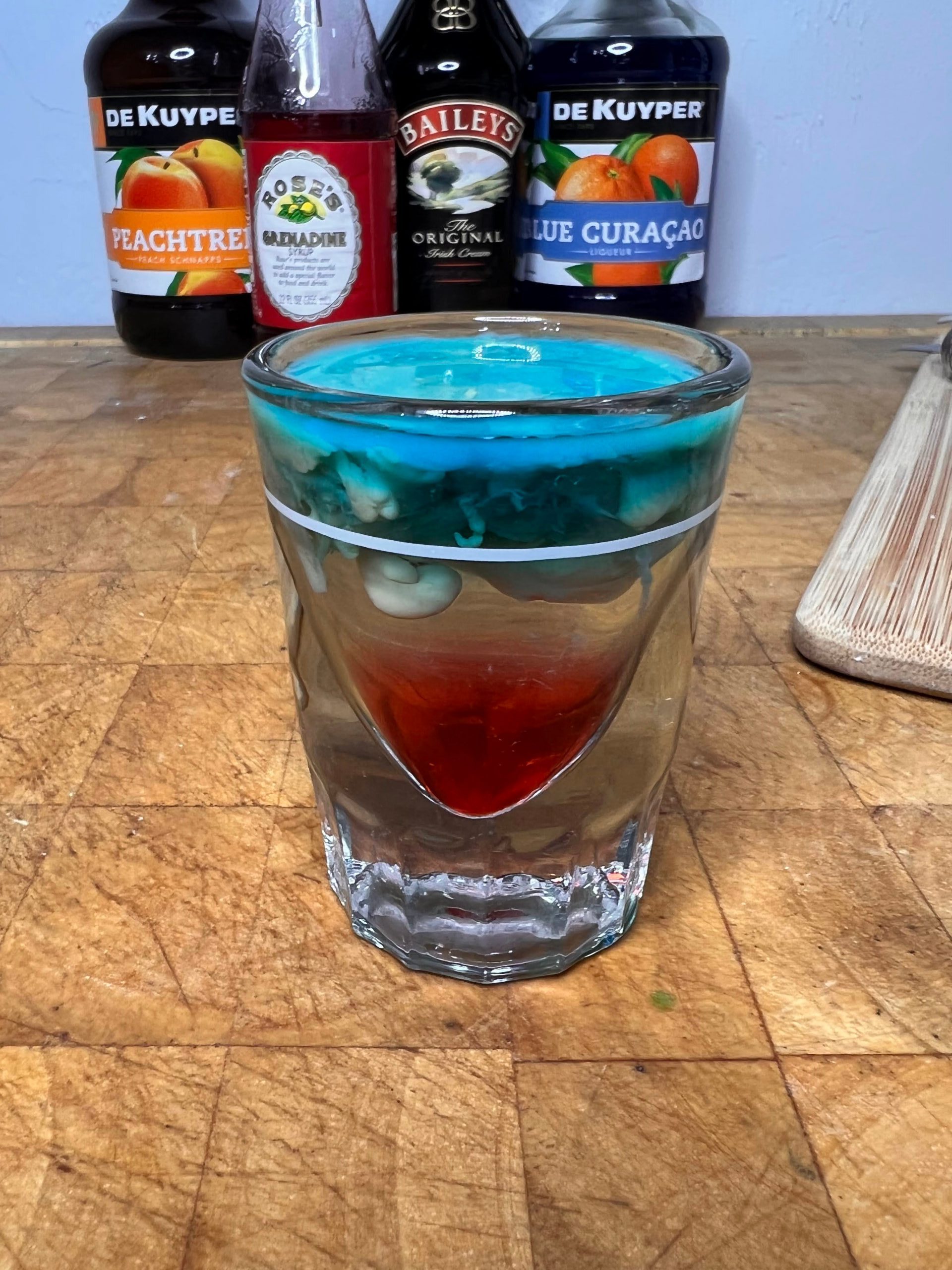 shot glass with alien brain hemmorage with liquor bottles visible in the background