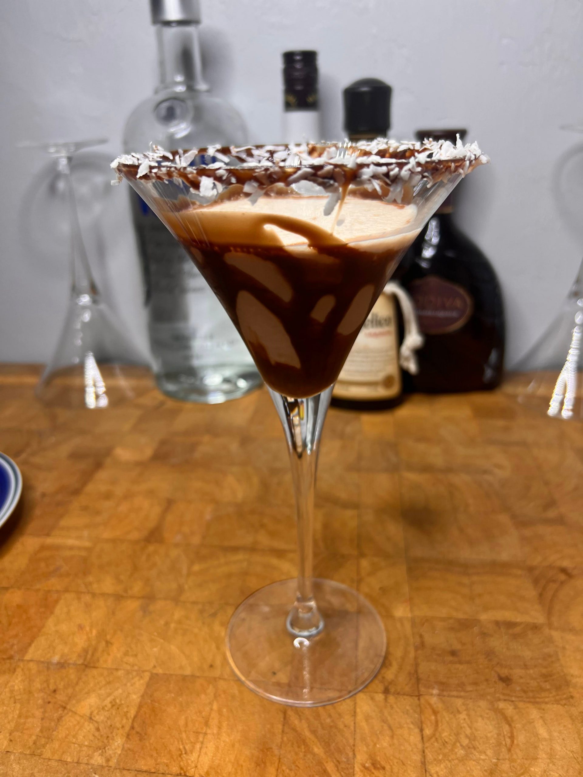 close up of almond joy martini  with liquor bottles visible in the background