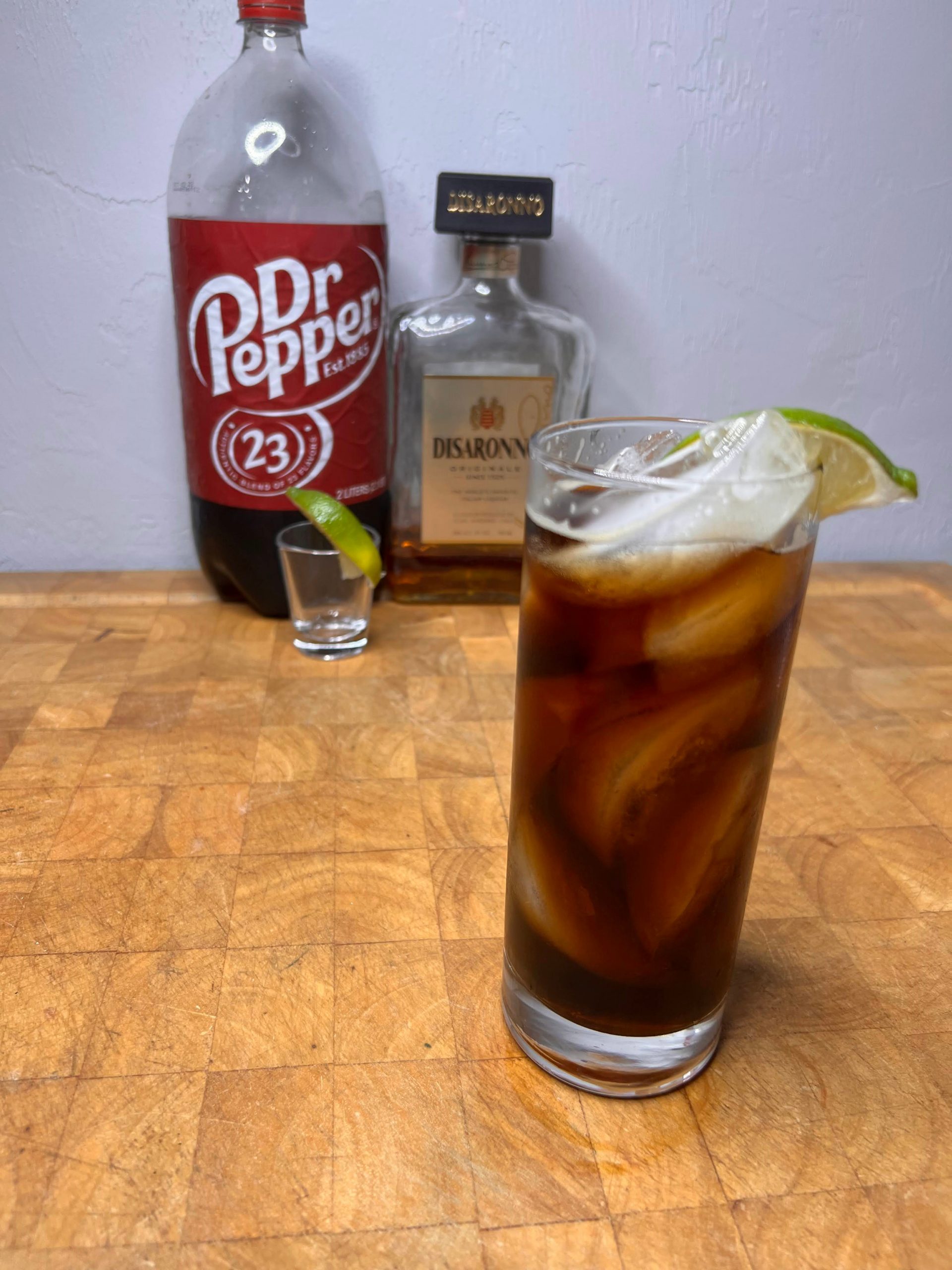 amaretto and dr pepper in glass with bottles in background