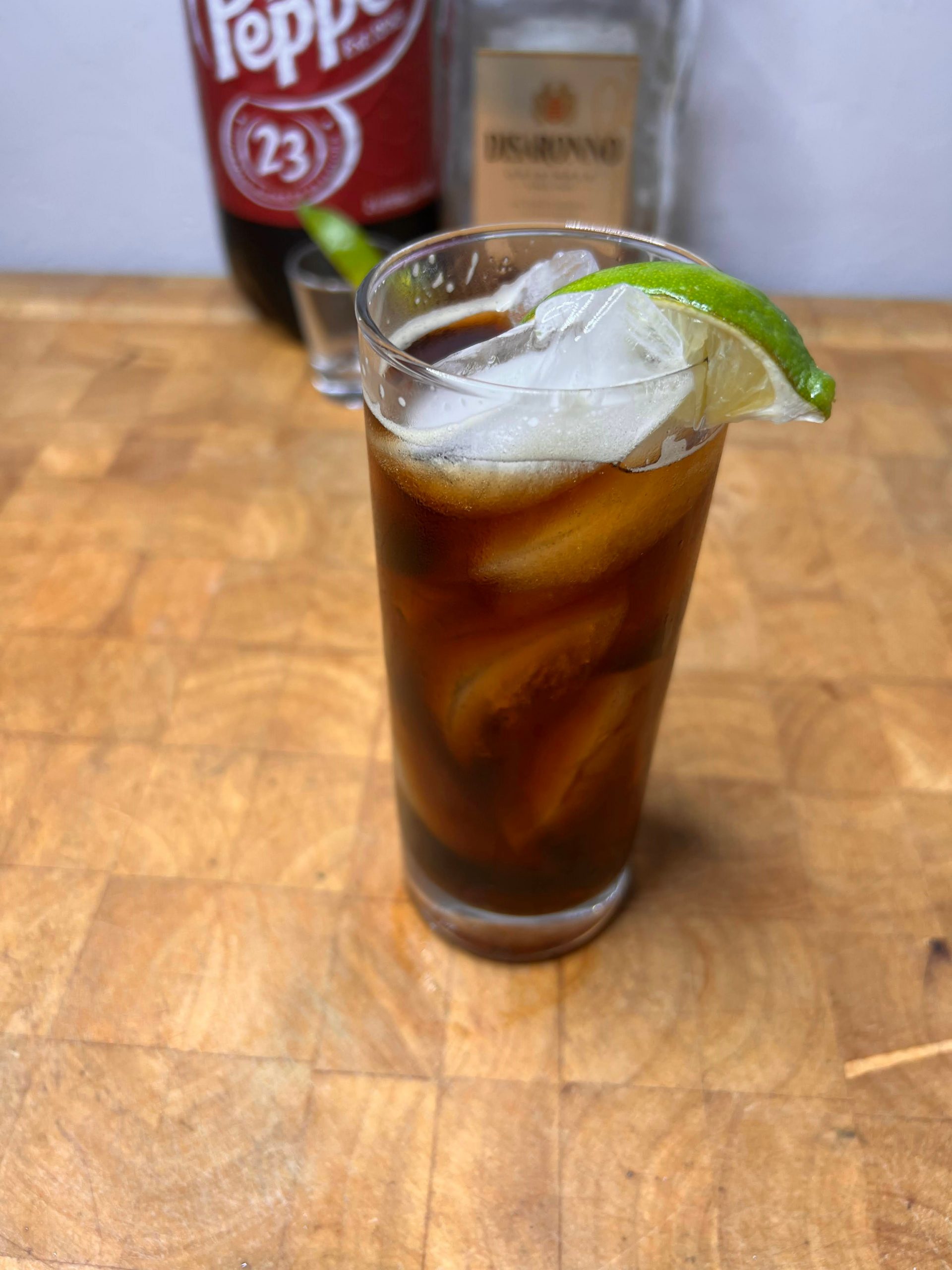amaretto and dr pepper in a glass on a butcher block