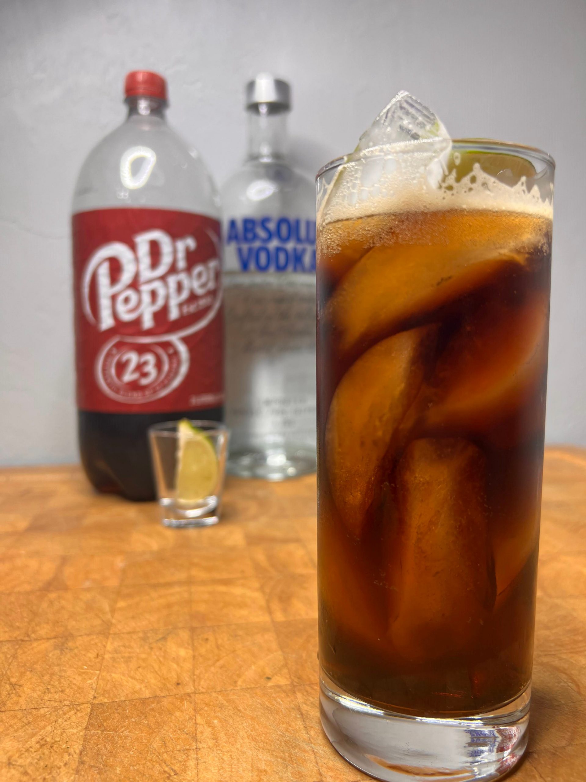 dr pepper and vodka in highball in front of bottles
