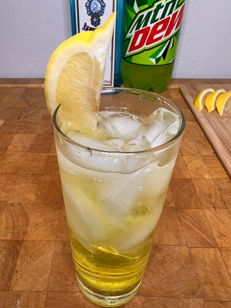 close up of gin & mountain dew with liquor bottles visible in the background
