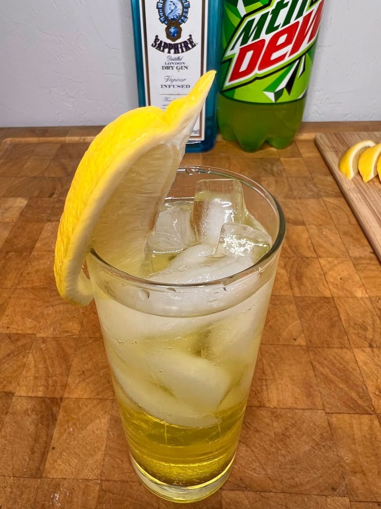 close up of gin & mountain dew with liquor bottles visible in the background