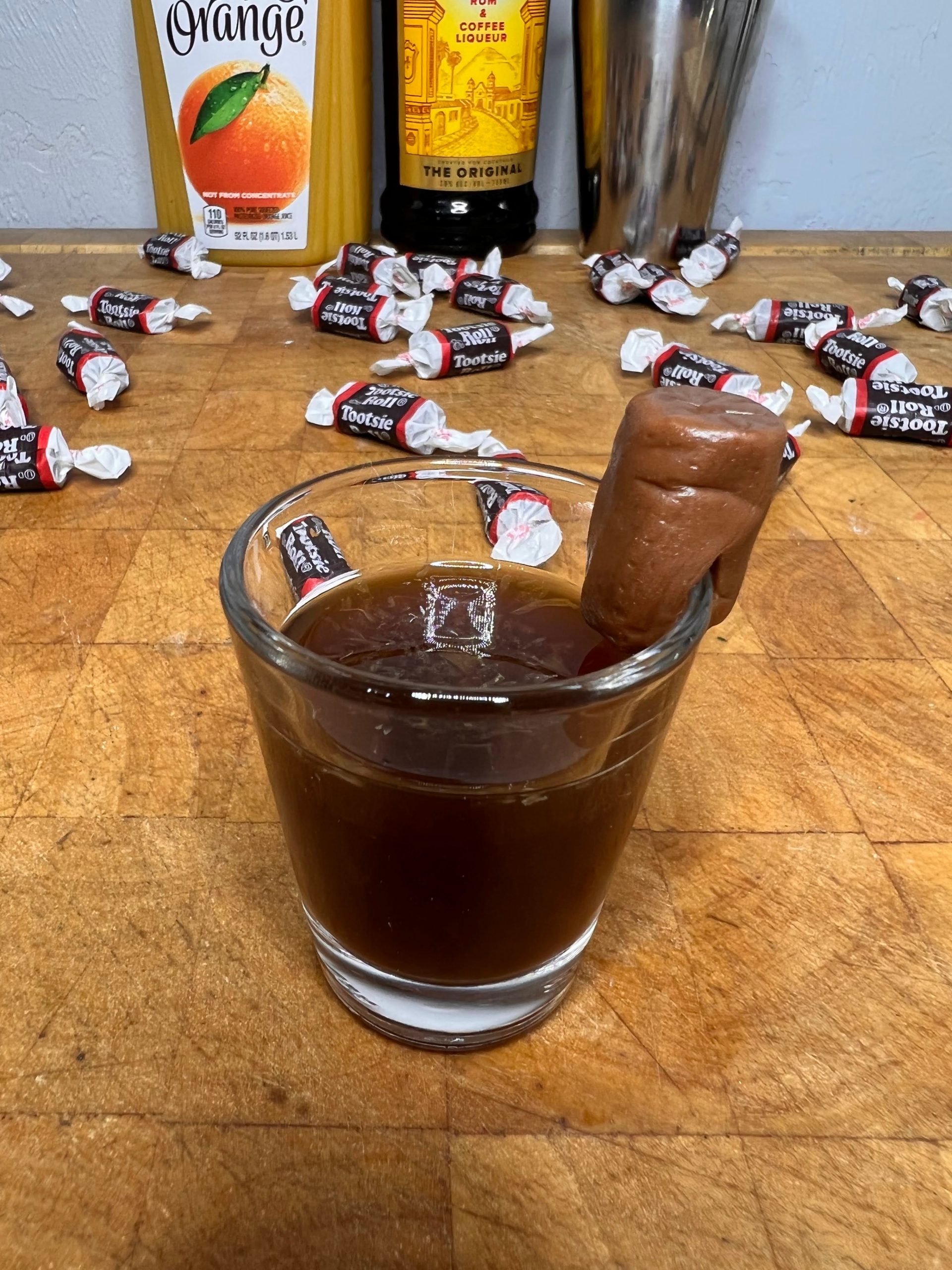 close up of tootsie roll shot with liquor bottles visible in the background