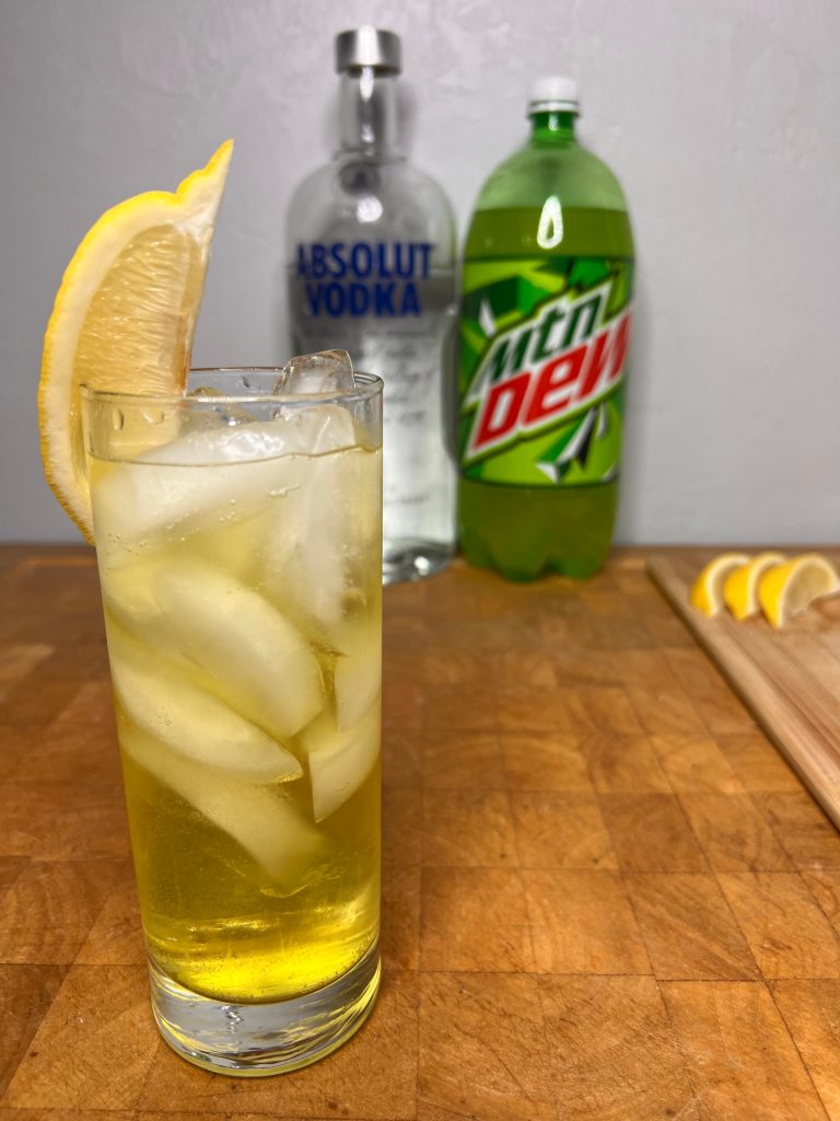 close up of vodka & mountain dew with liquor bottles visible in the background