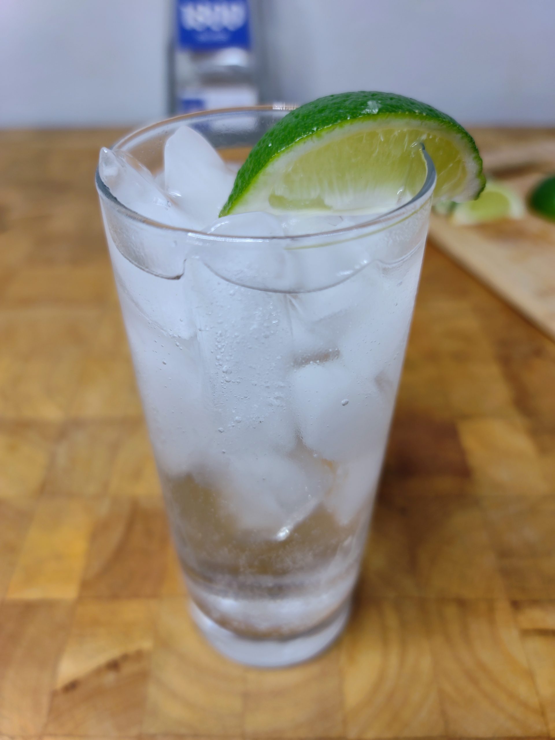 closeup of tequila and soda water with lime wedge