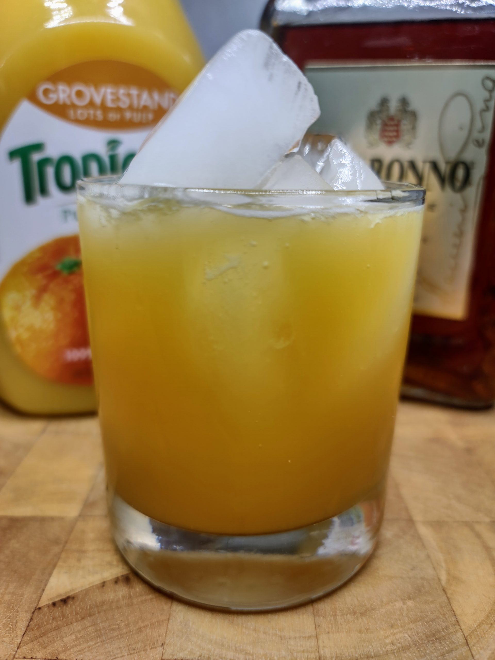 amaretto and orange juice in a glass with ingredients behind it