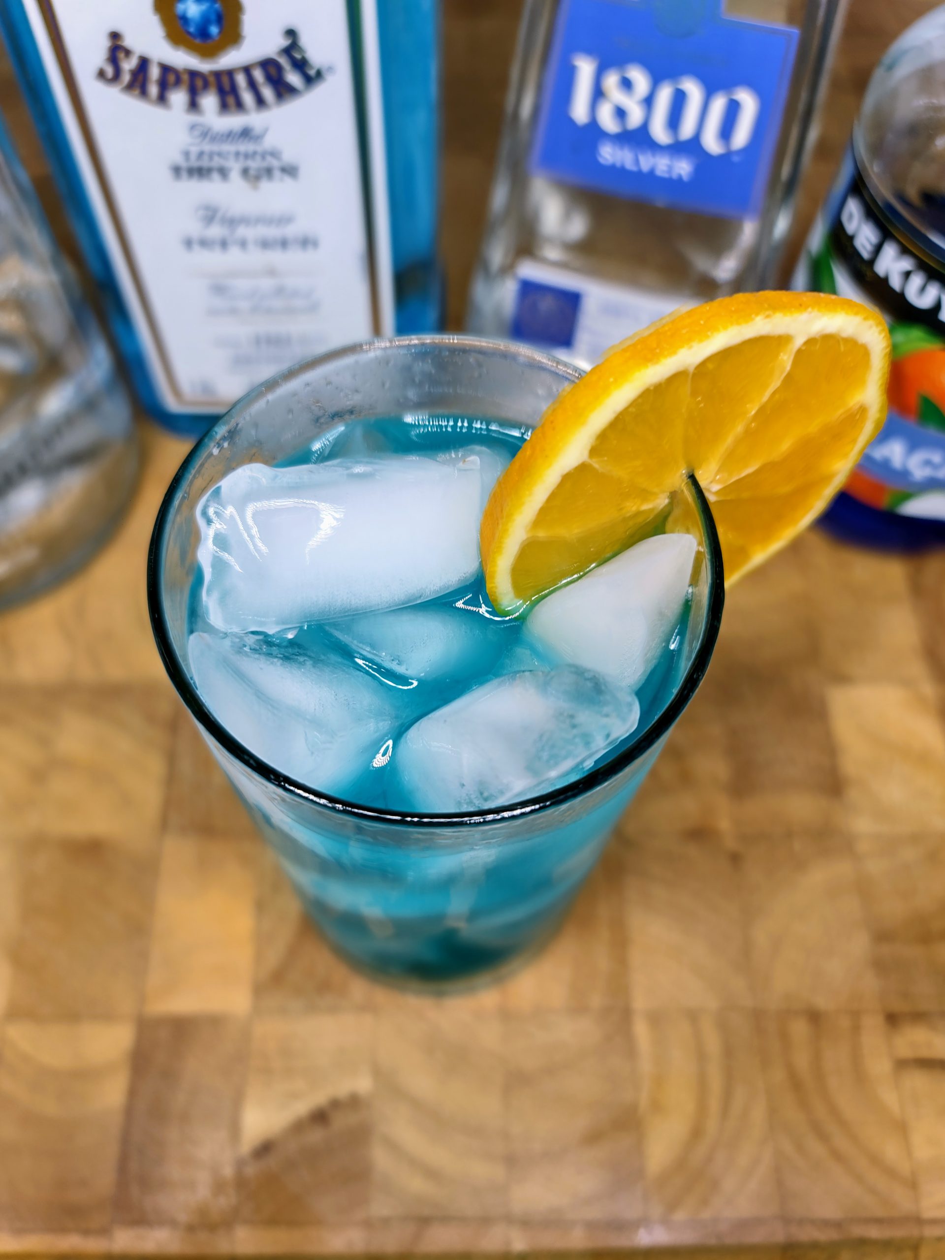 top down view of blue motorcycle cocktail with bottles in background