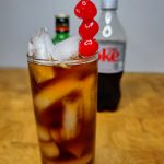 jager and coke cocktail with cherry garnish on wooden table
