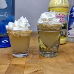 two key lime pie shots with bottles behind it