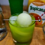 melon ball drink with bottles behind glass