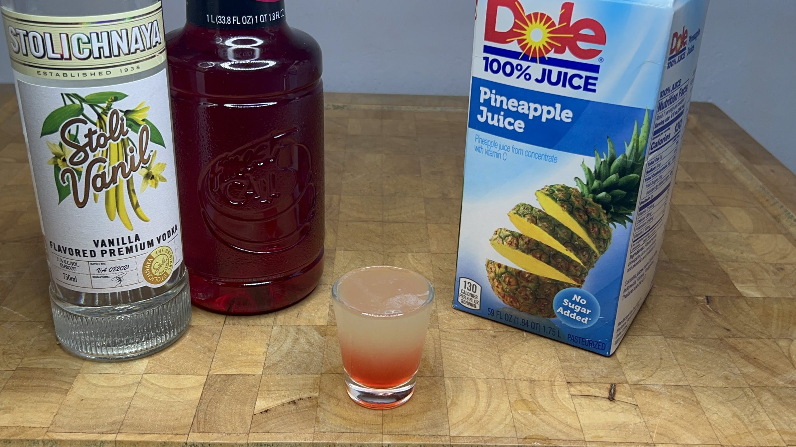 pineapple upside down shot with ingredients next to glass