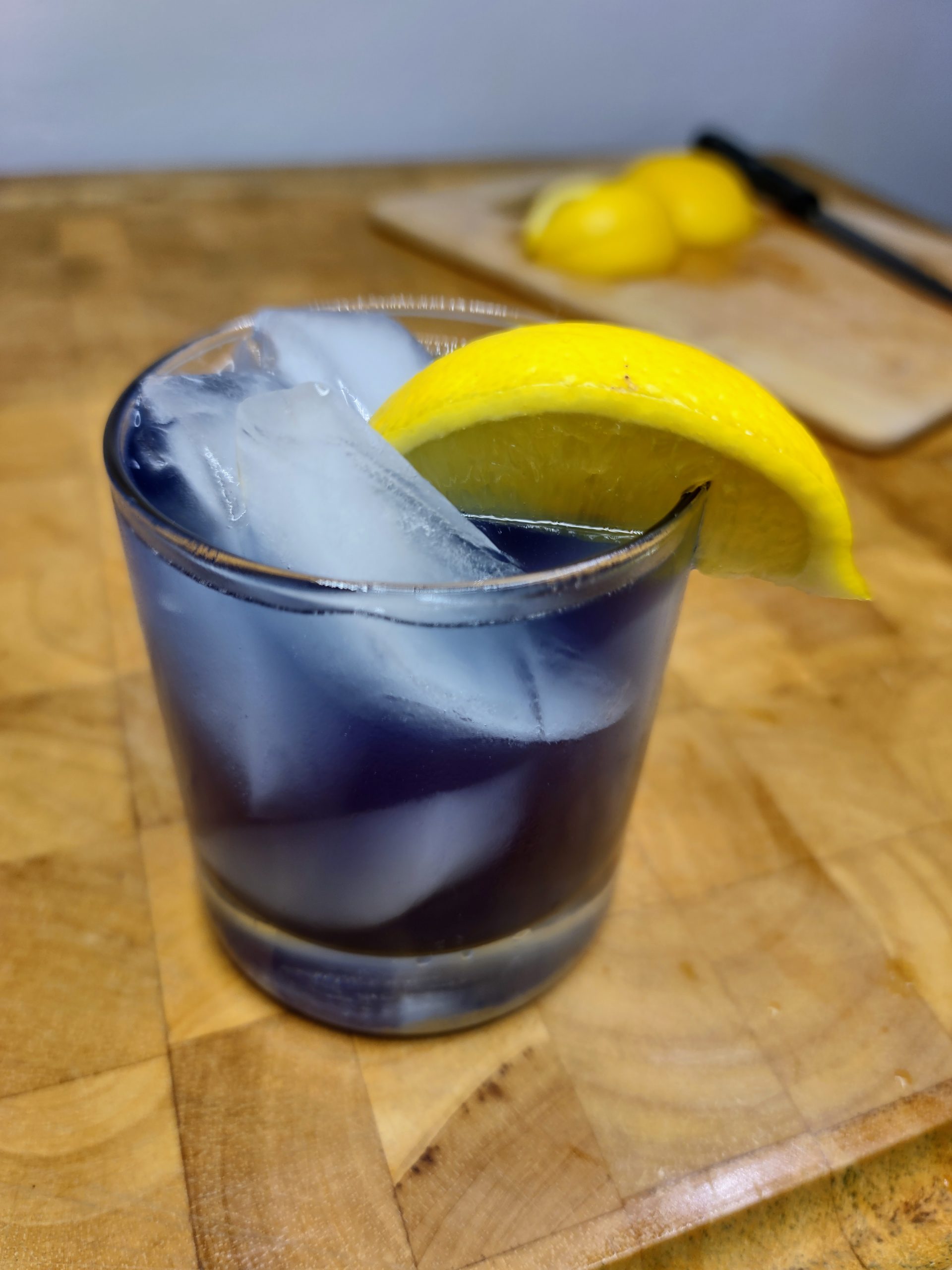 purple rain drink with lemon wedge in background