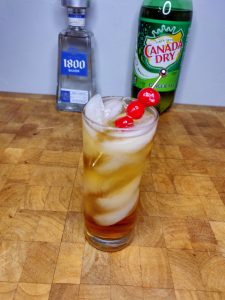 glass of tequila and gingerale with cherry garnish
