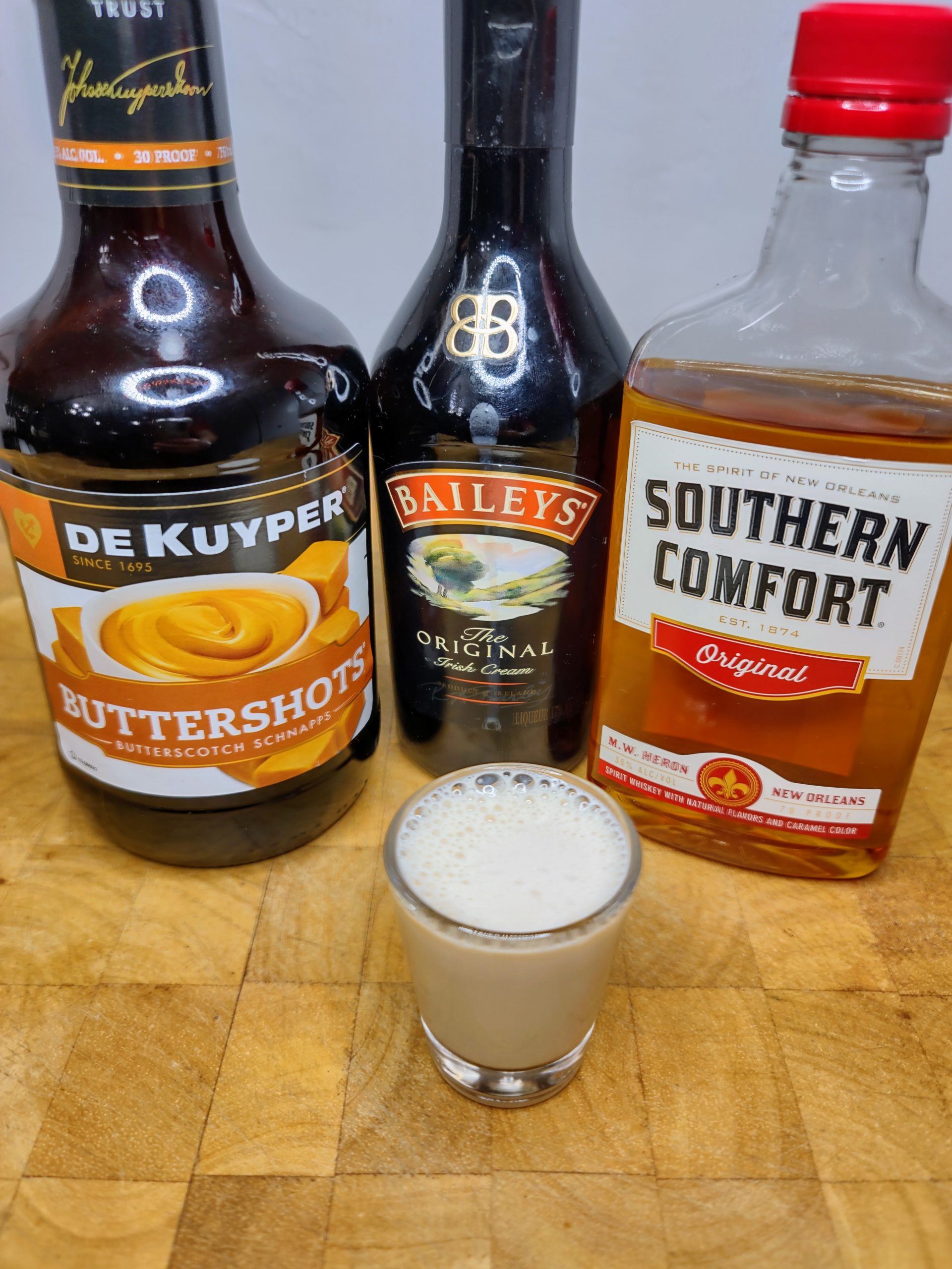 butterscotch schnapps drink - cowboy cocksucker shot with ingredients behind the glass