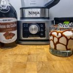 frozen brandy alexander in a rocks glass next to blender and other ingredients