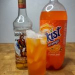 orange soda and vodka highball with ingredients behind the drink