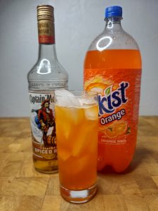 orange soda and vodka highball with ingredients behind the drink