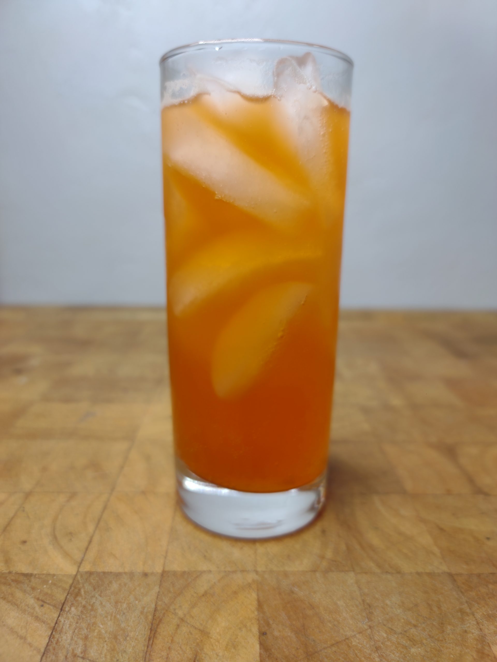 closeup of orange soda and vodka in a highball glass on a wooden table