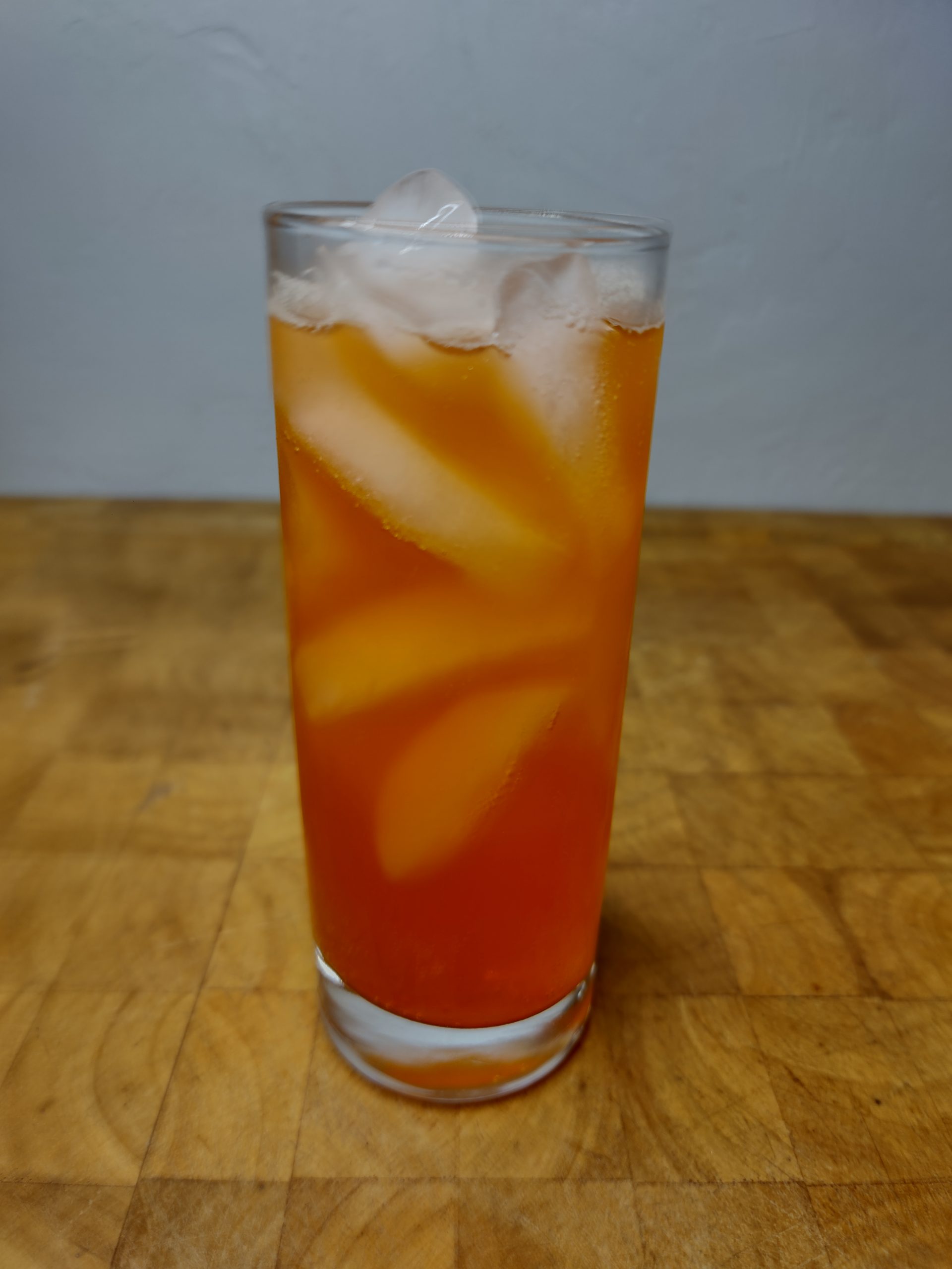 closeup of orange soda with vodka in a highball glass on a wooden table