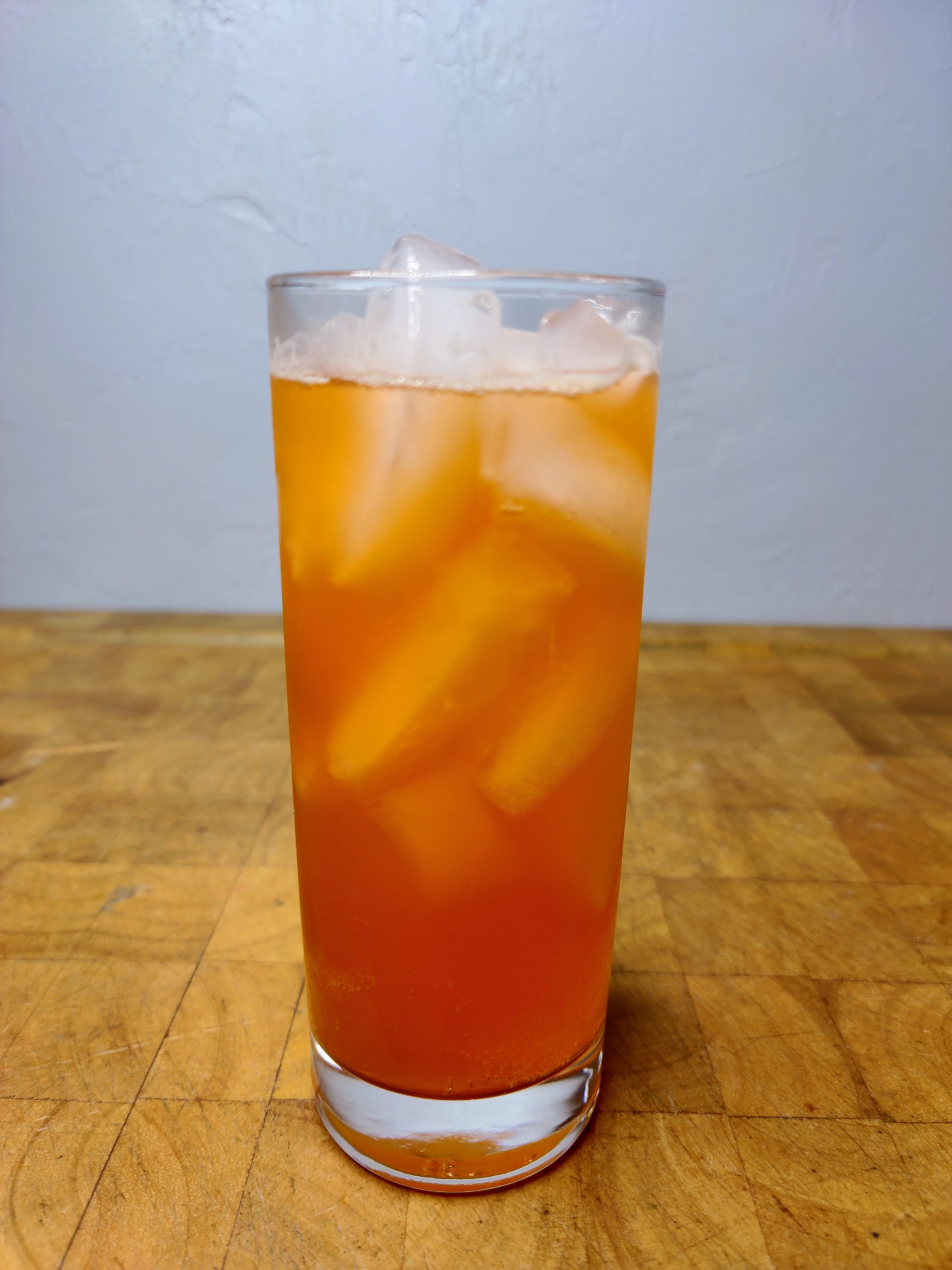 closeup of whiskey and orange soda in a highball glass on a wooden table