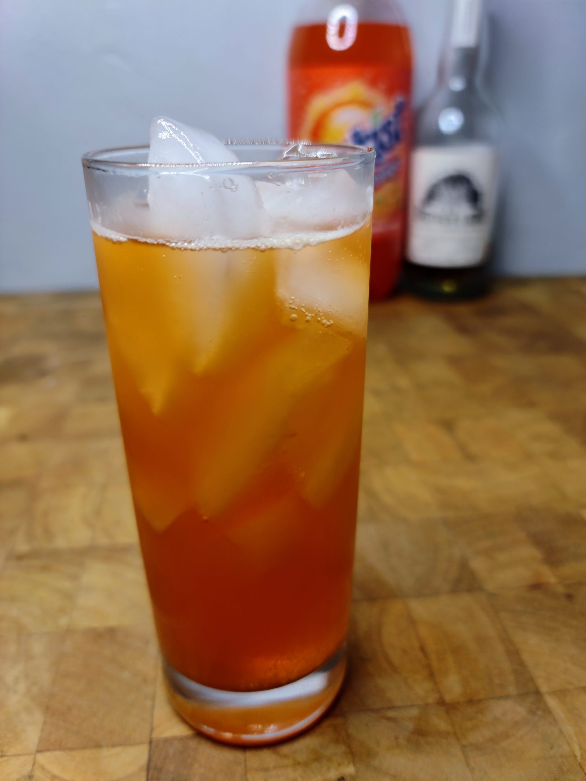 whiskey and orange soda in a highball glass with ingredients in the background