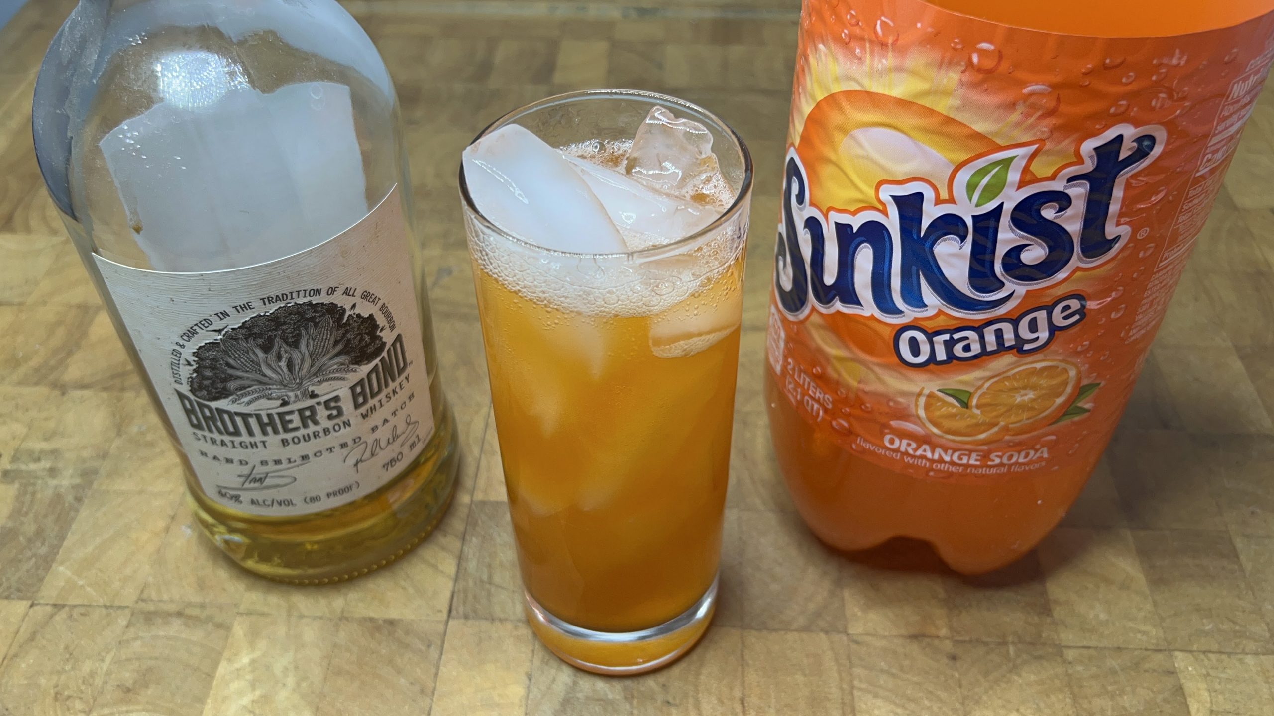 orange soda and whiskey cocktail with ingredients next to the glass