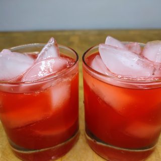 two red cocktails in rocks glasses on wooden table
