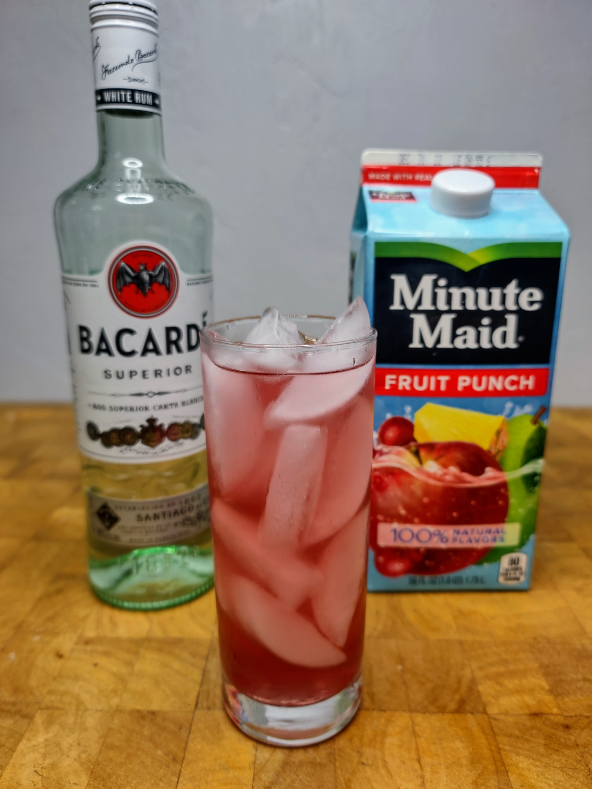 rum and fruit punch with ingredients next to highball glass