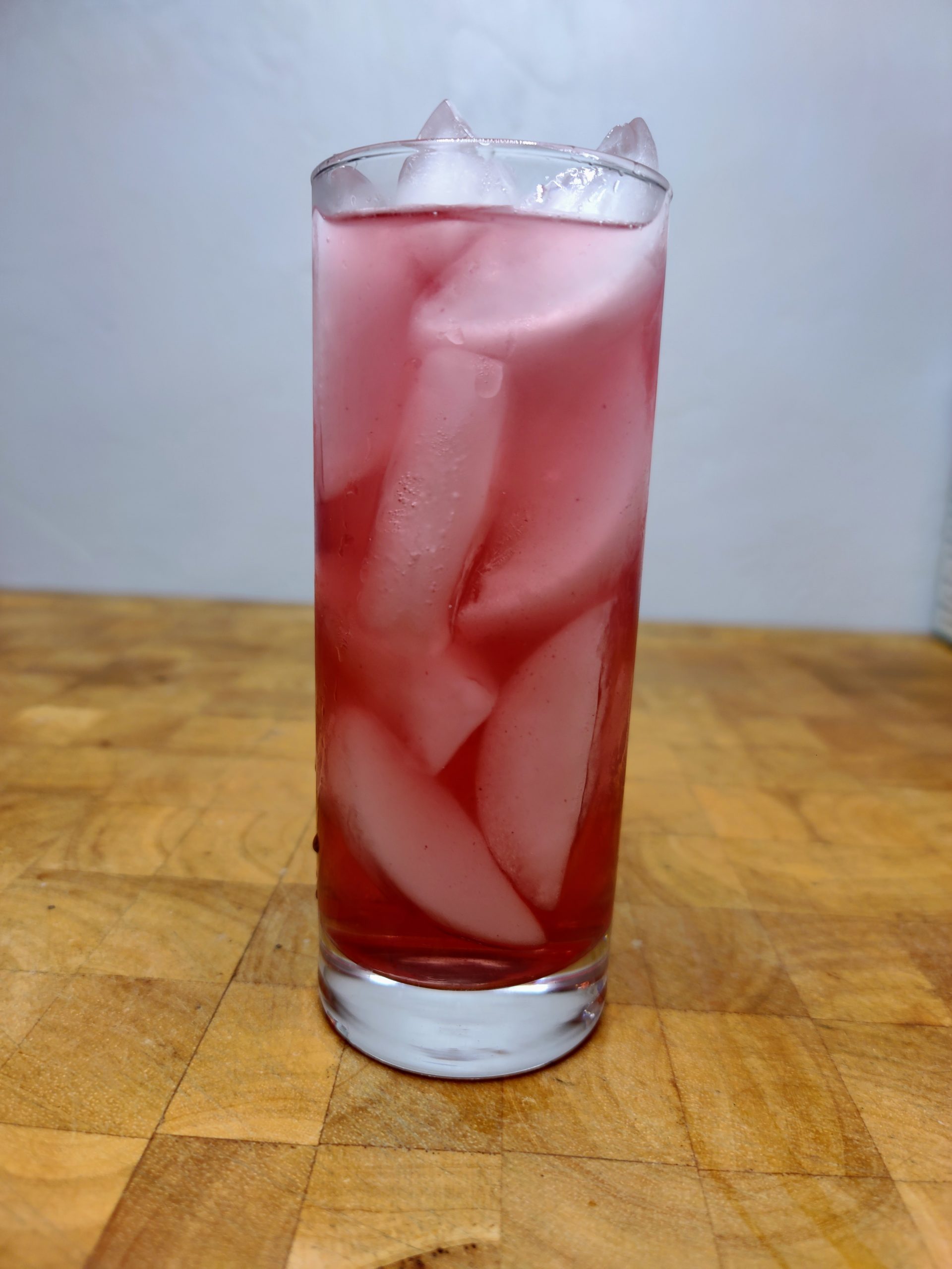 closeup of vodka and fruit punch in a highball glass on a wooden table