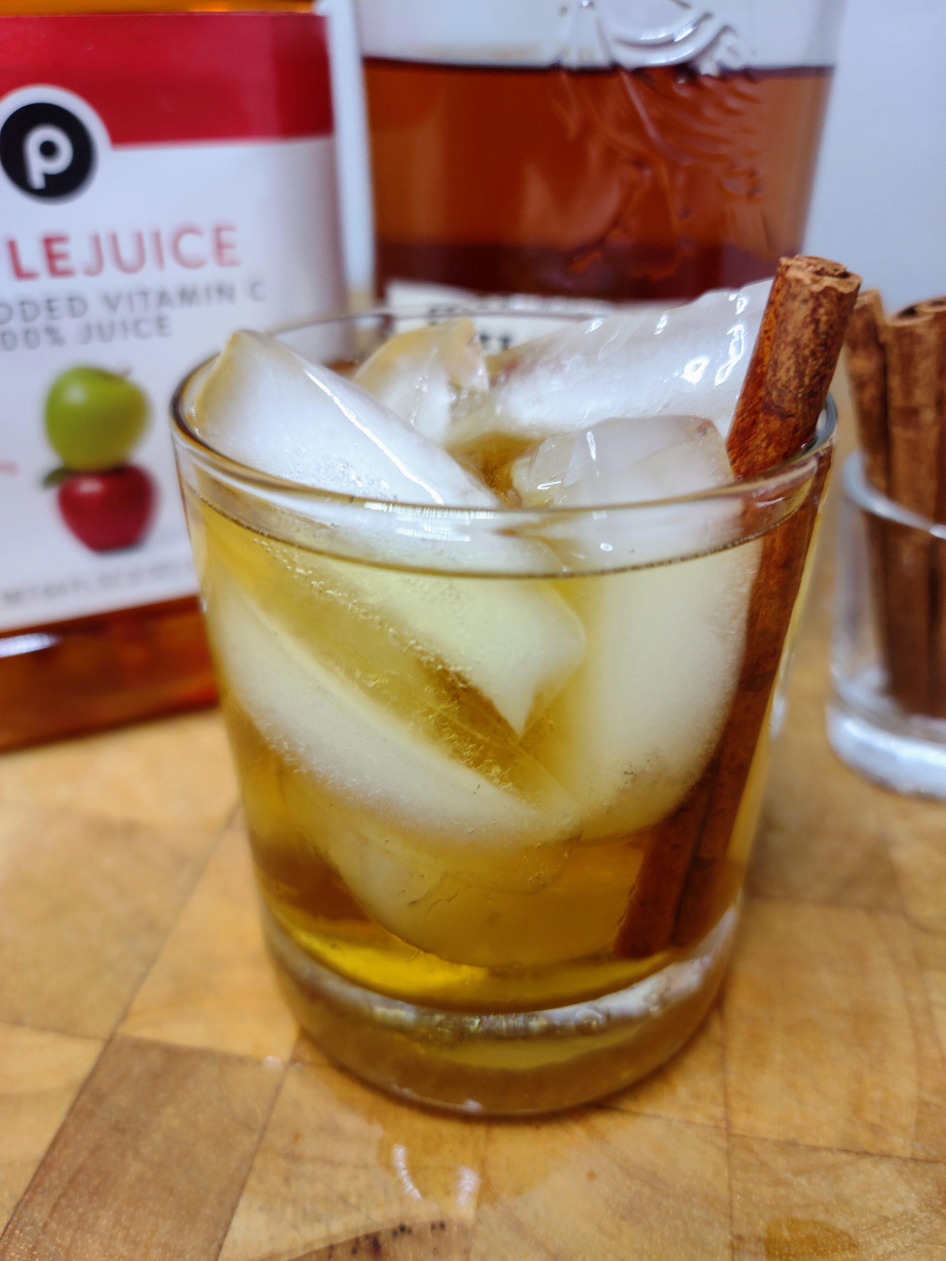 whiskey and apple juice with ingredients behind the drink