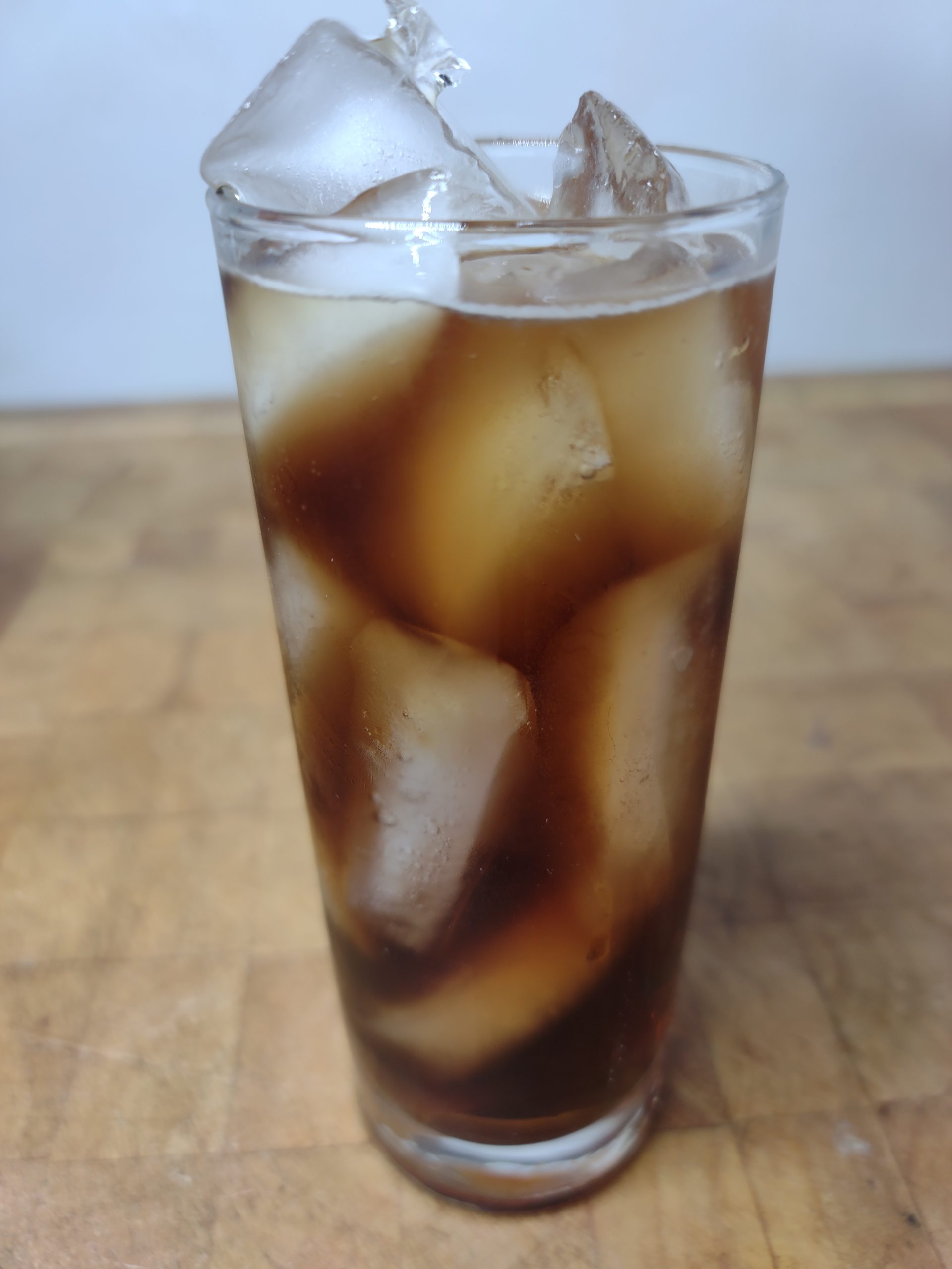 closeup of a crown and coke in a highball glass on a wooden table