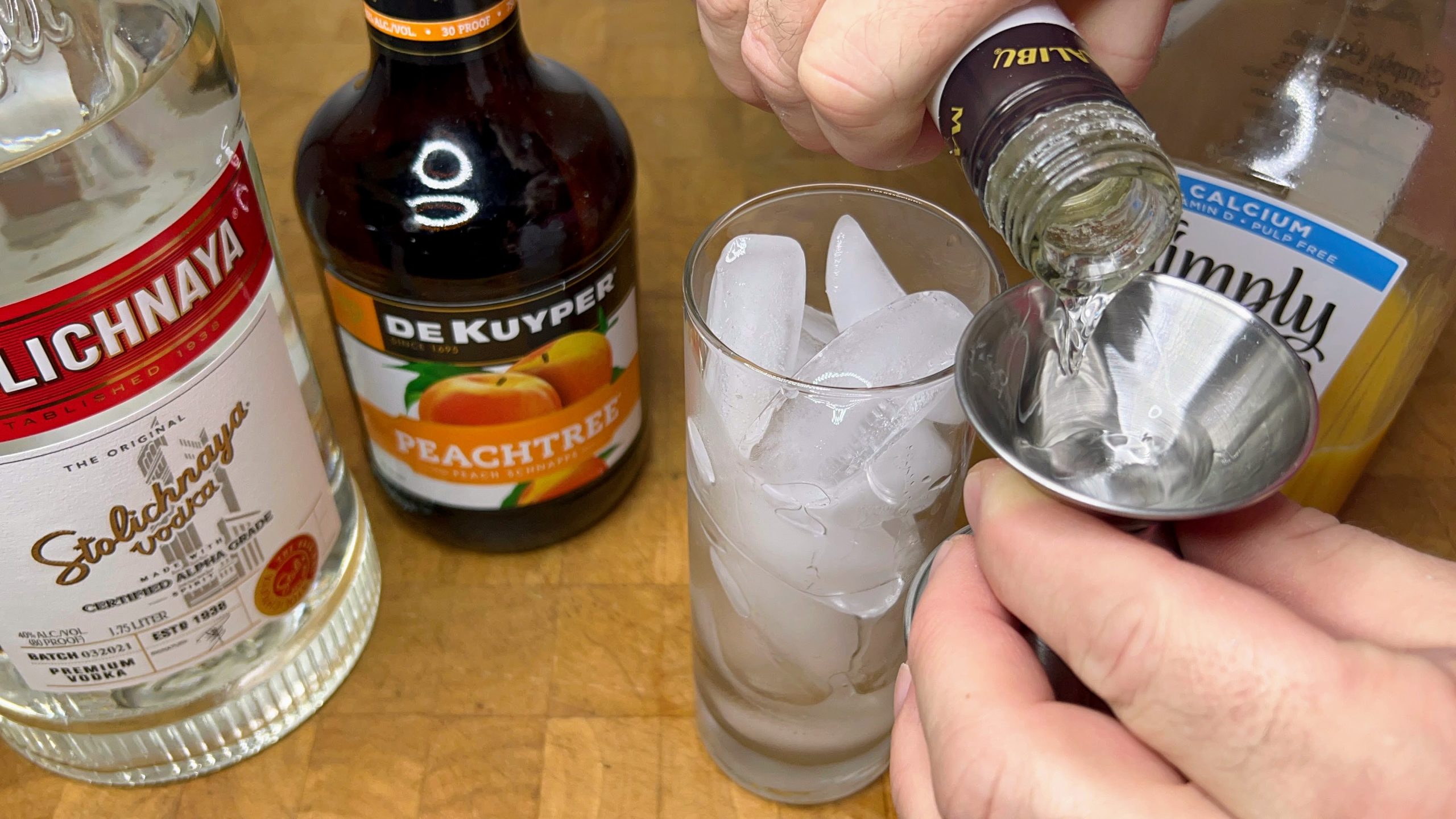 measuring coconut rum with a jigger