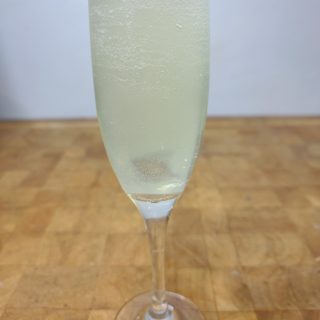 close up of french 75 cocktail in champagne flute on a wooden table