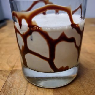 frozen brandy alexander in a rocks glass with chocolate syrup inside it.