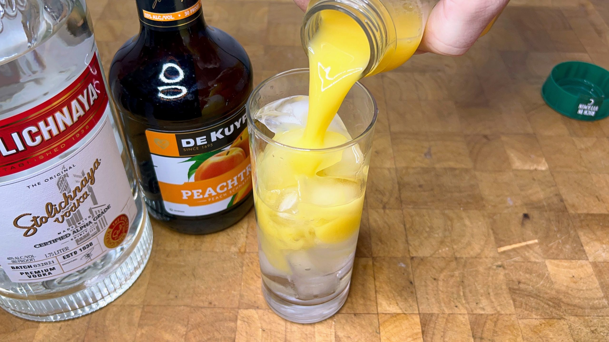 pouring orange juice into a highball glass