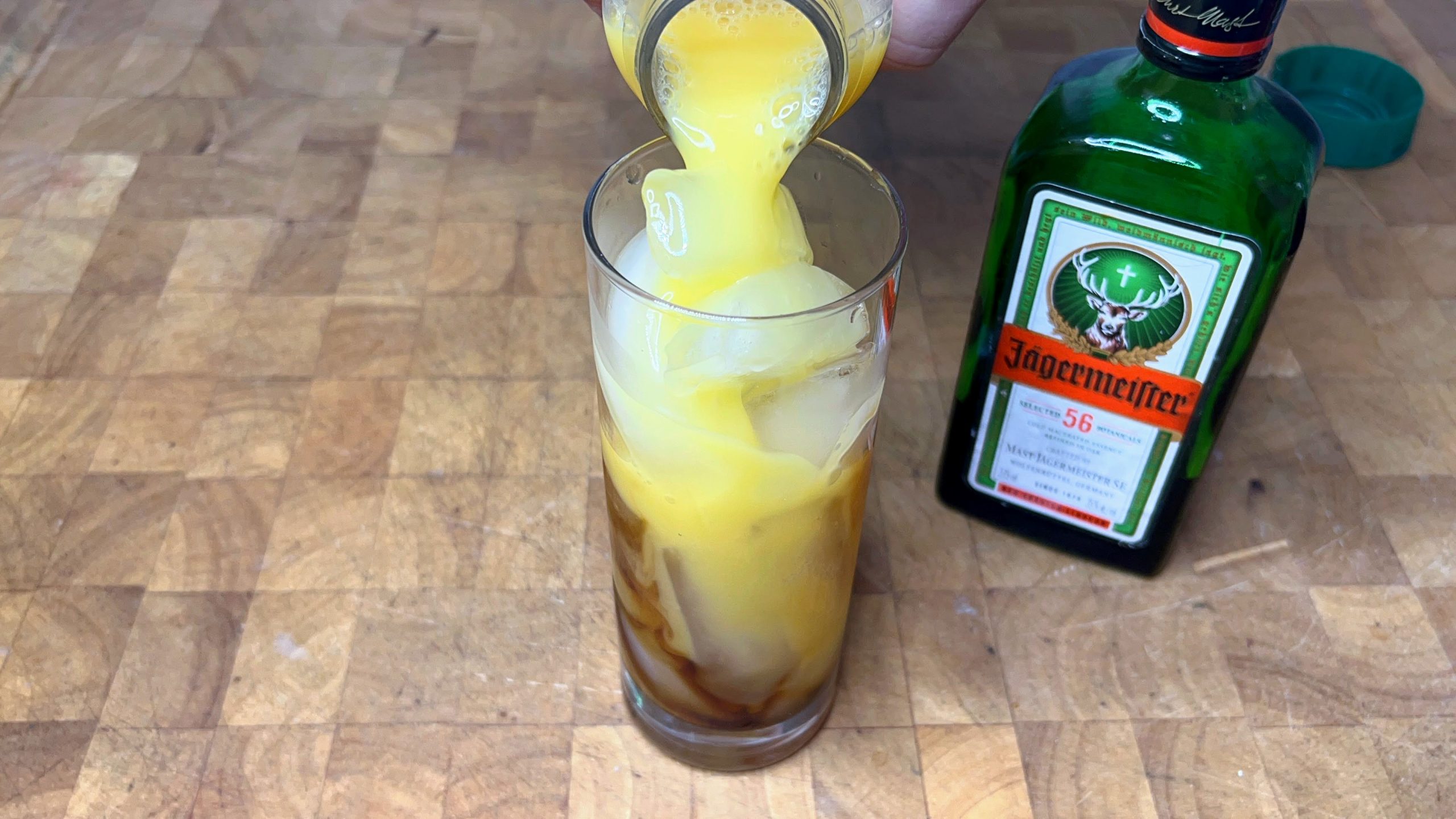pouring orange juice into a glass with jager