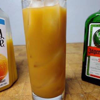 jager and orange juice in a highaball glass on a wooden table