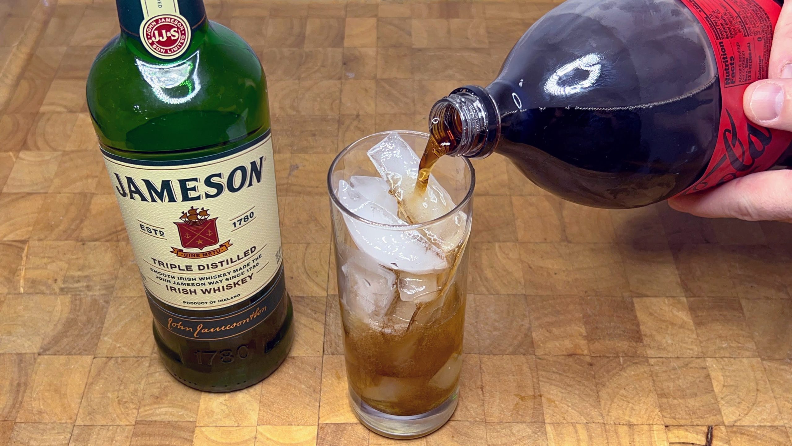 pouring coke into highball glass with jamesons