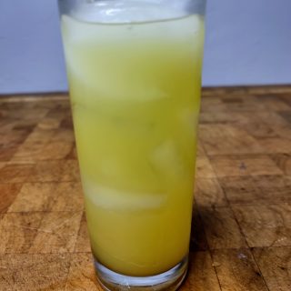 closeup of orange gin and tonic in a highball glass on a wooden table