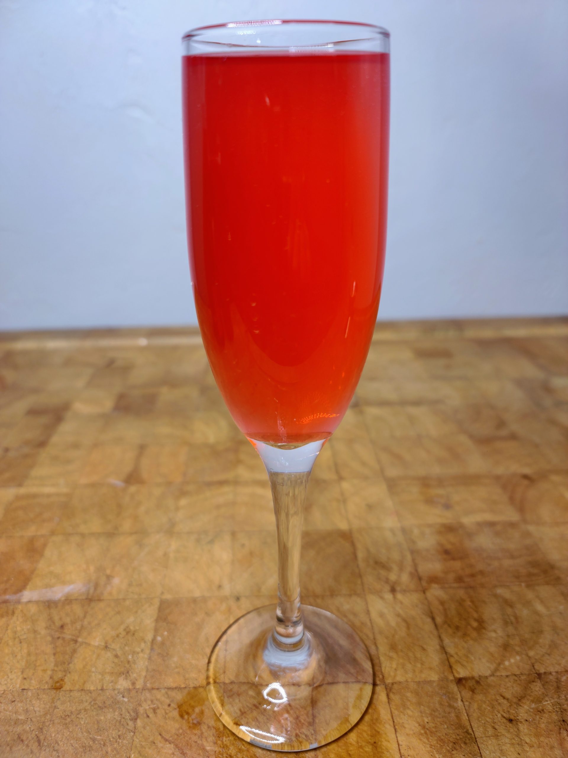 closeup of passionfruit mimosa in a champagne flute on a wooden table