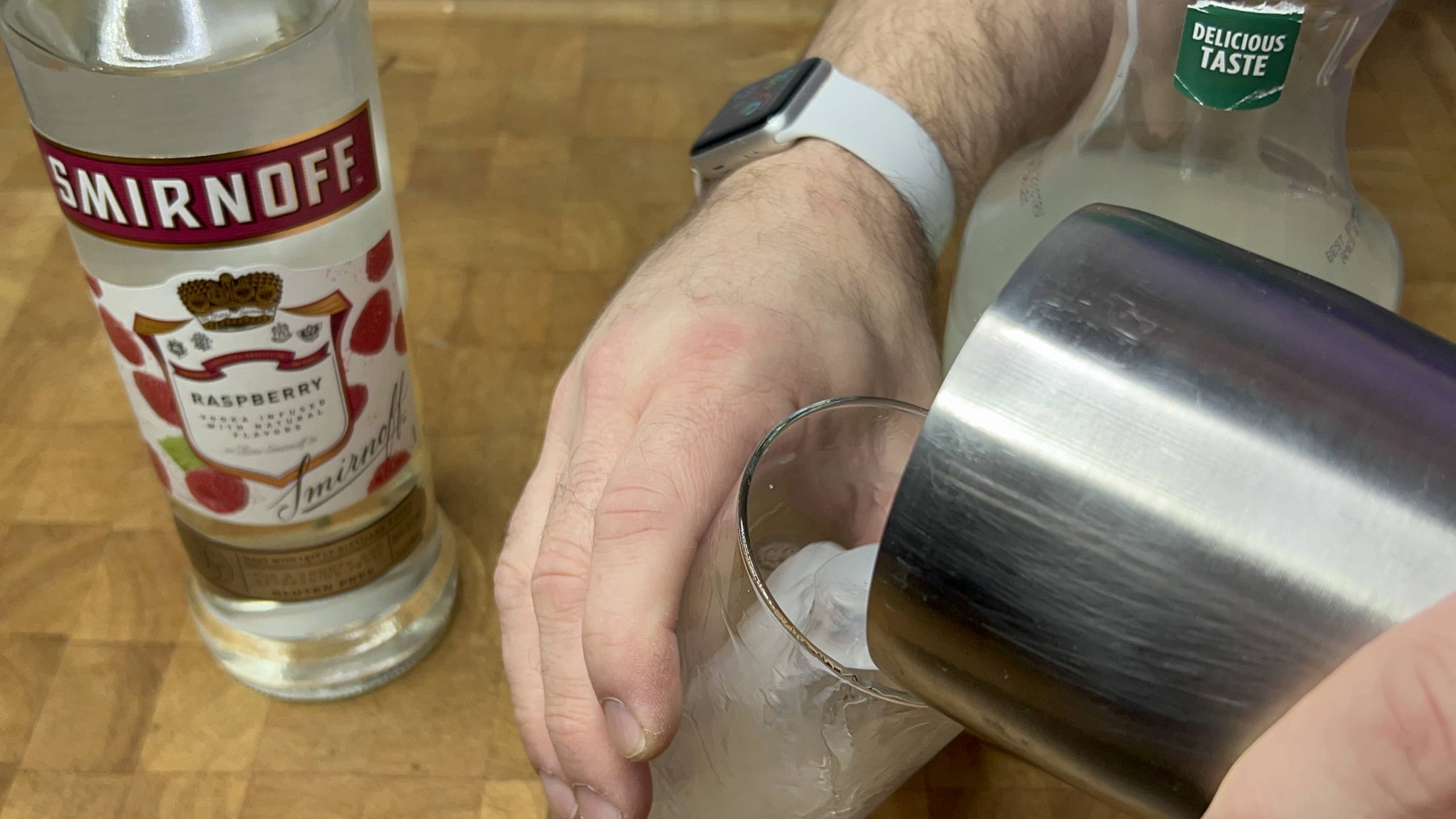 Pouring drink from shaker into highball glass