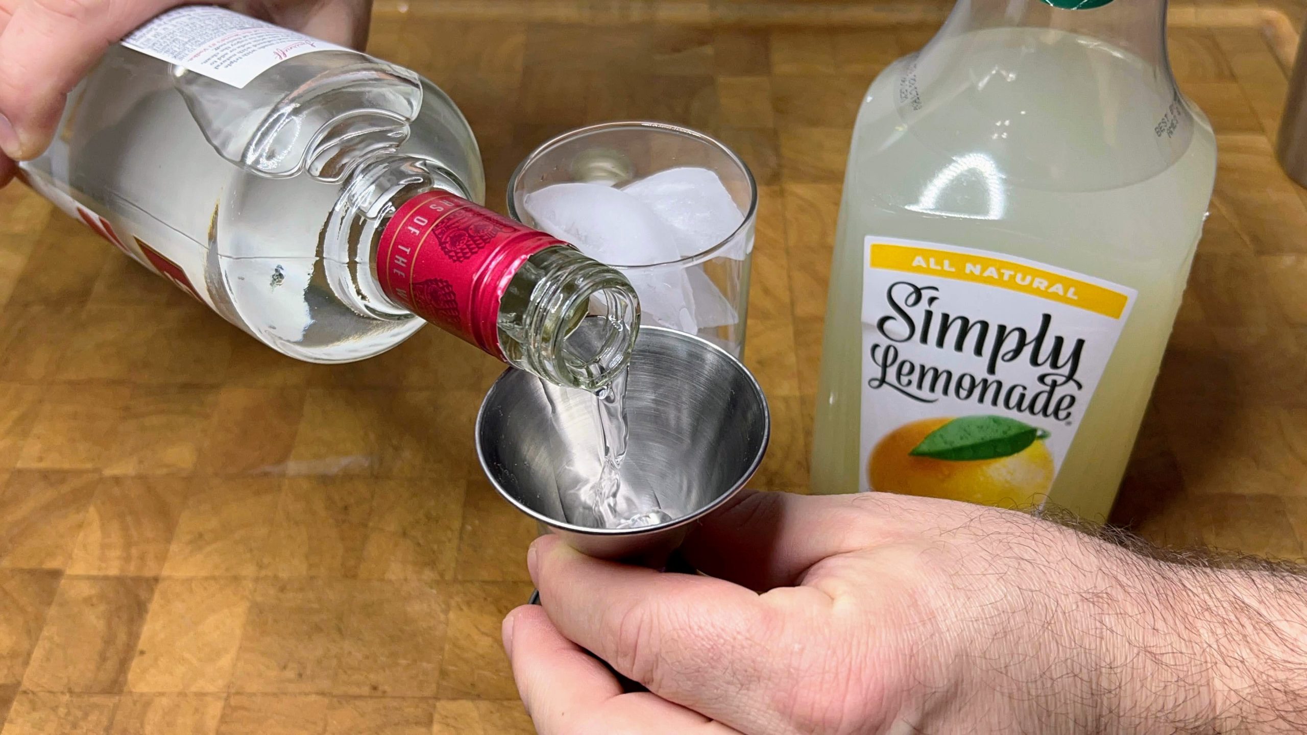 pouring vodka into a jigger to measure it