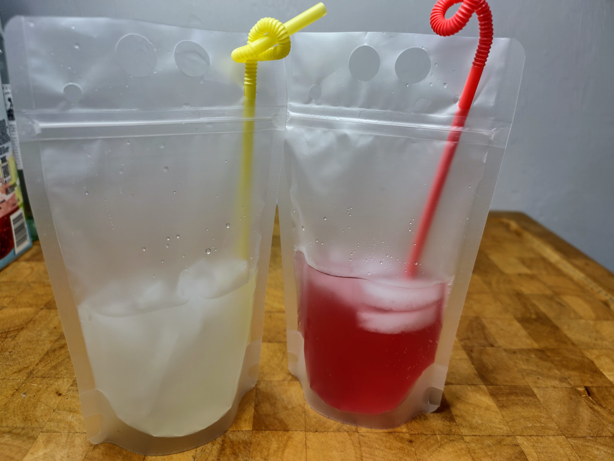 two adult capri suns on a wooden table.  One made with lemonade and the other made with fruit punch