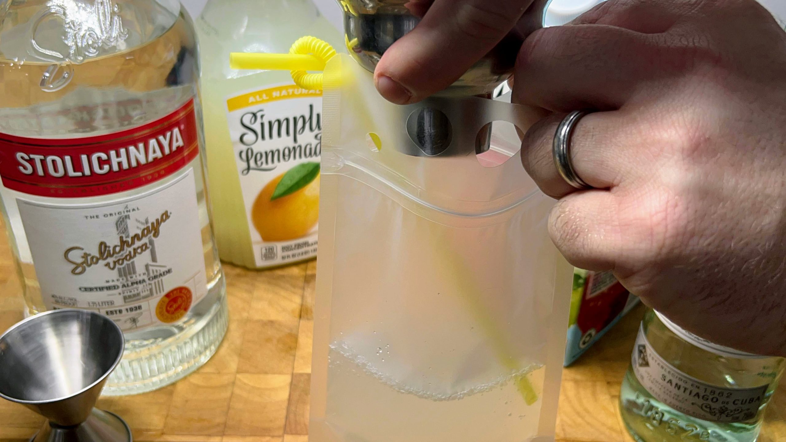 pouring drink from cocktail shaker into plastic drink pouch