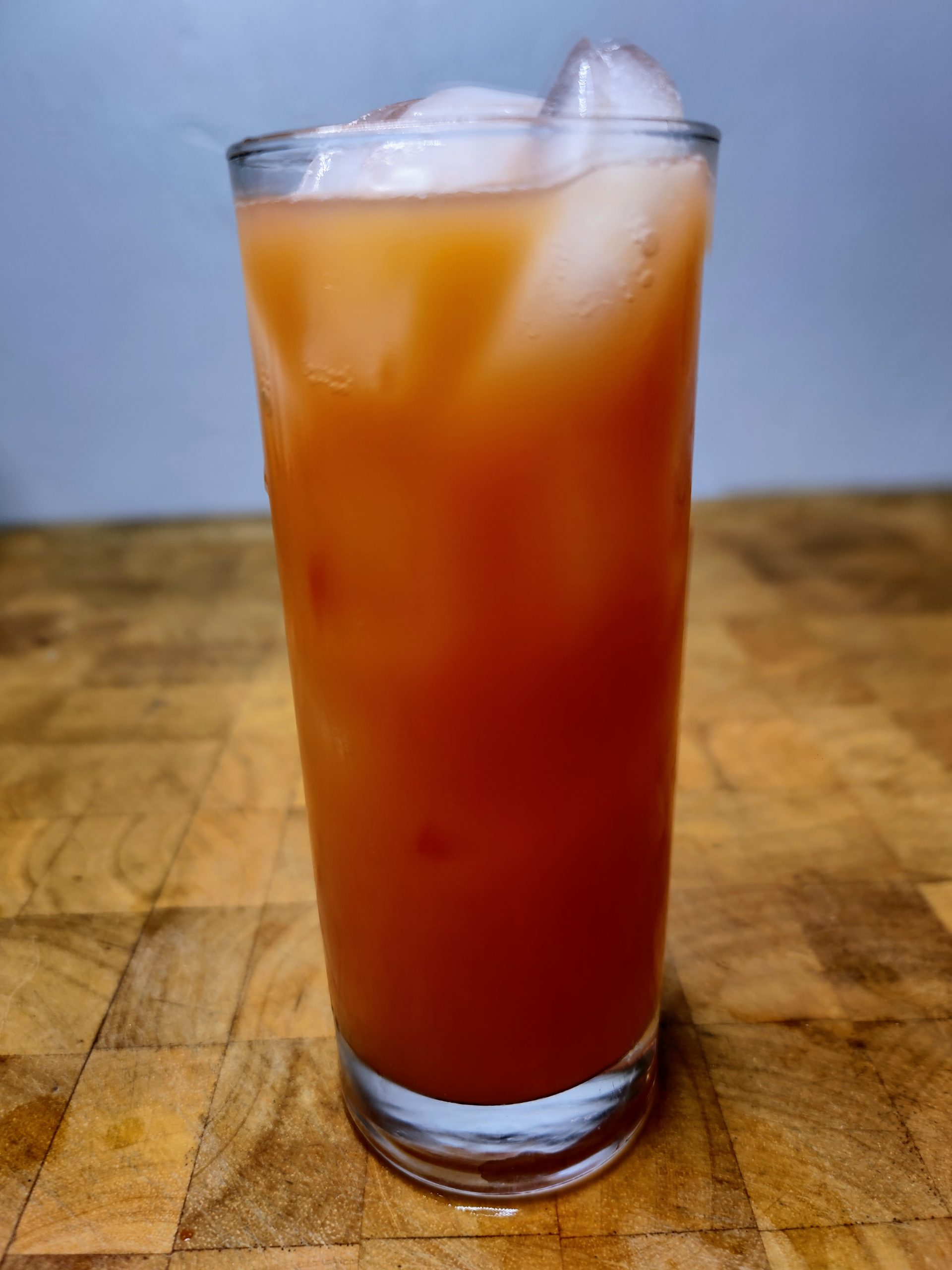red death drink in a highball glass on a wooden table