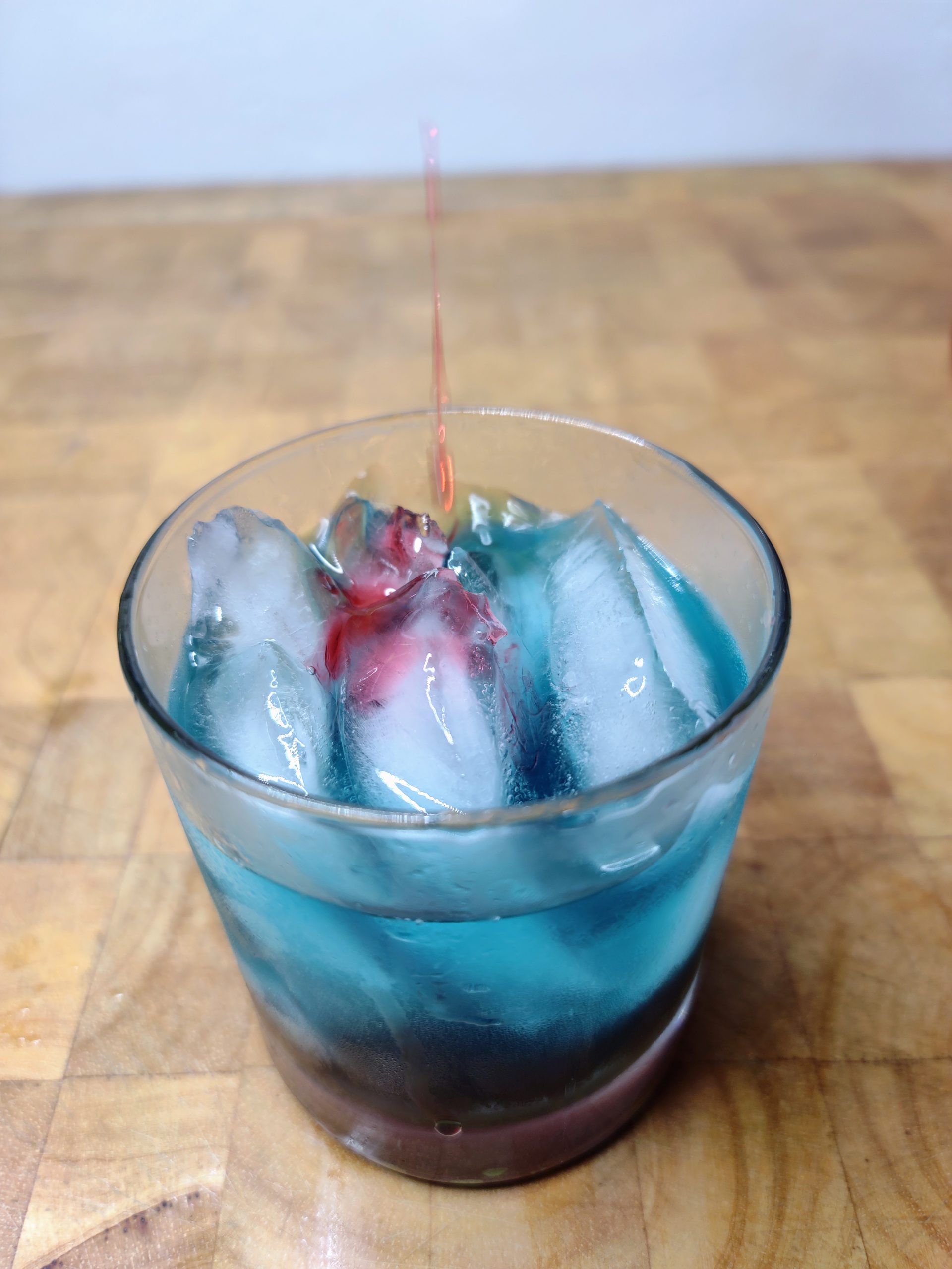 closeup of shark bite drink in a rocks glass on a wooden table