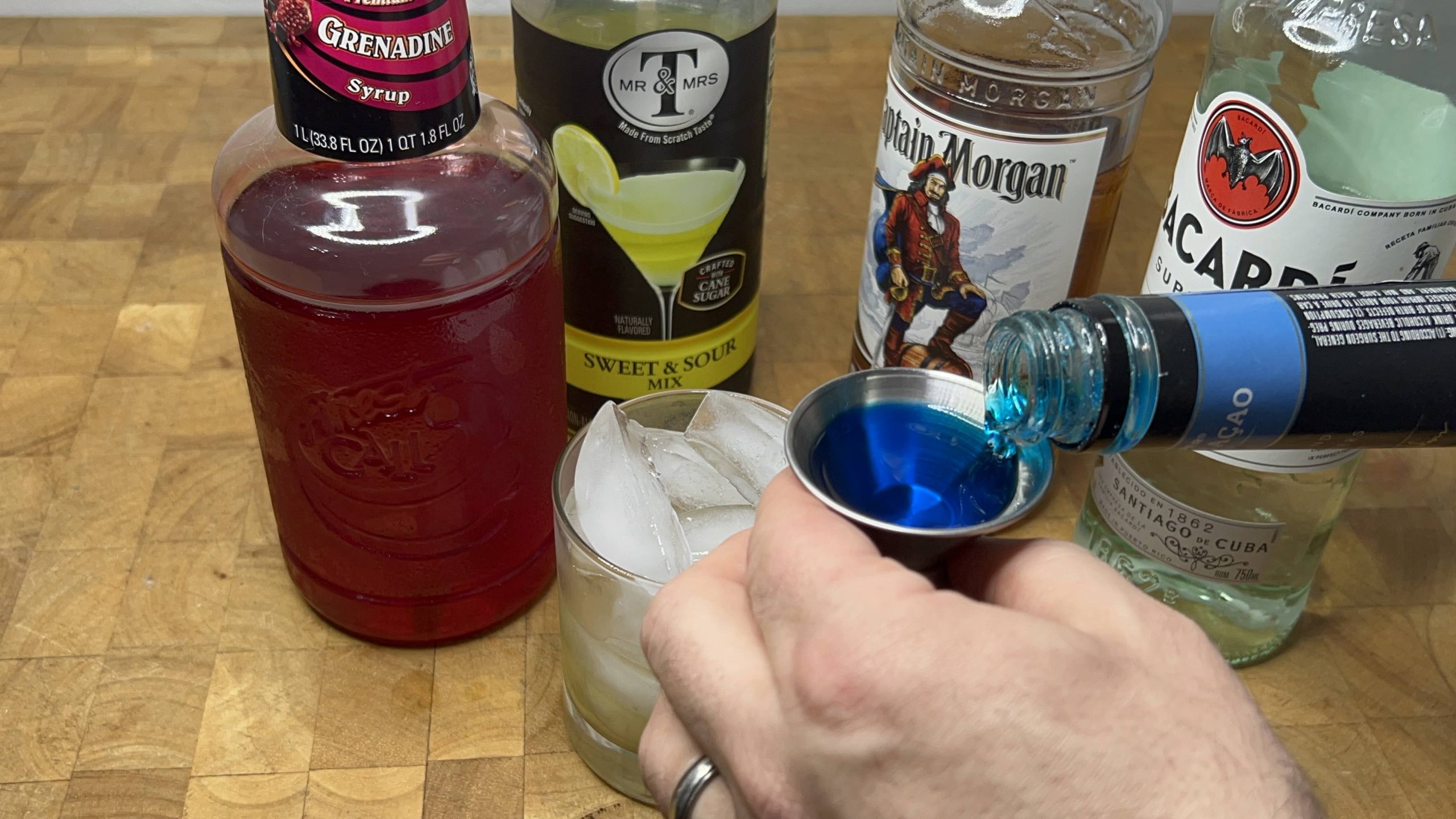 pouring blue curacao in a jigger
