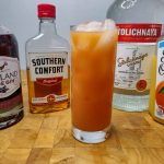 slow comfortable screw drink in a highball glass in front of the ingredients used to make it