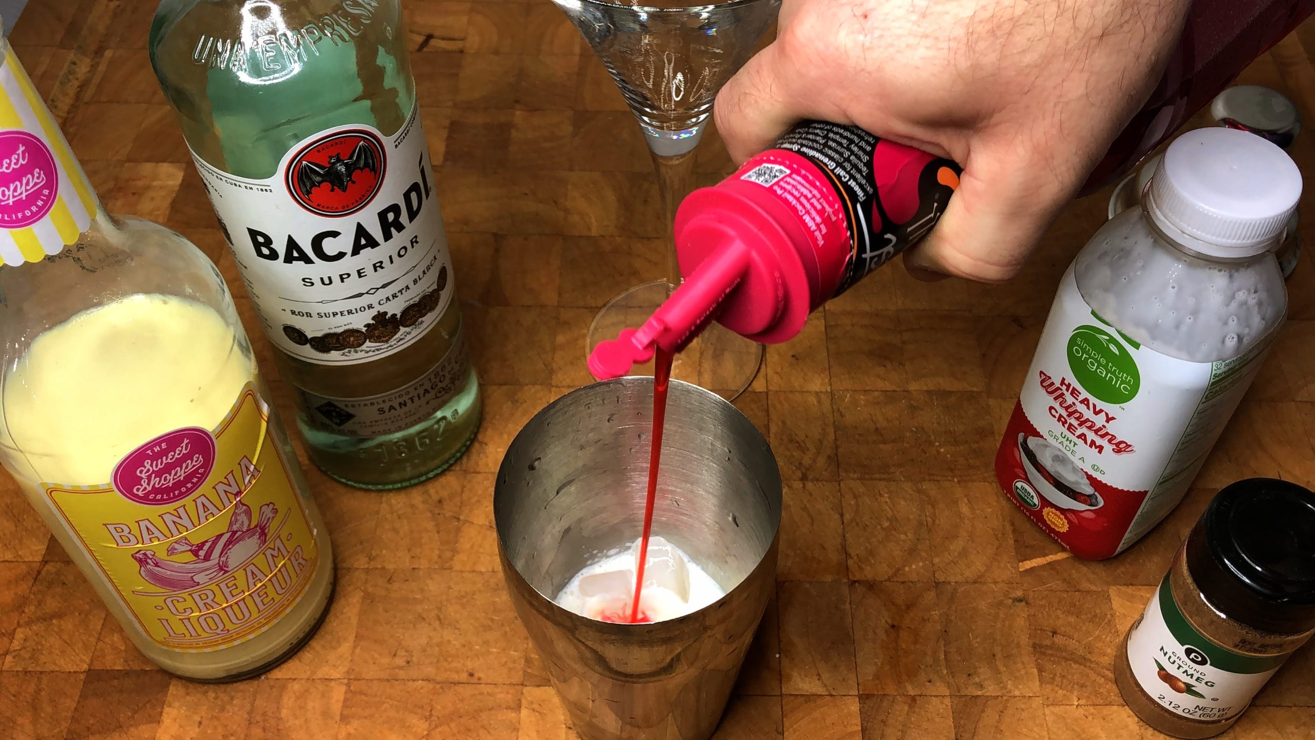 pouring grenadine into a cocktail shaker